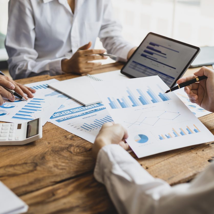 Business meeting, brainstorming sessions discuss analysis of investment growth graph and market charts in financial reports and business investment strategy planning.